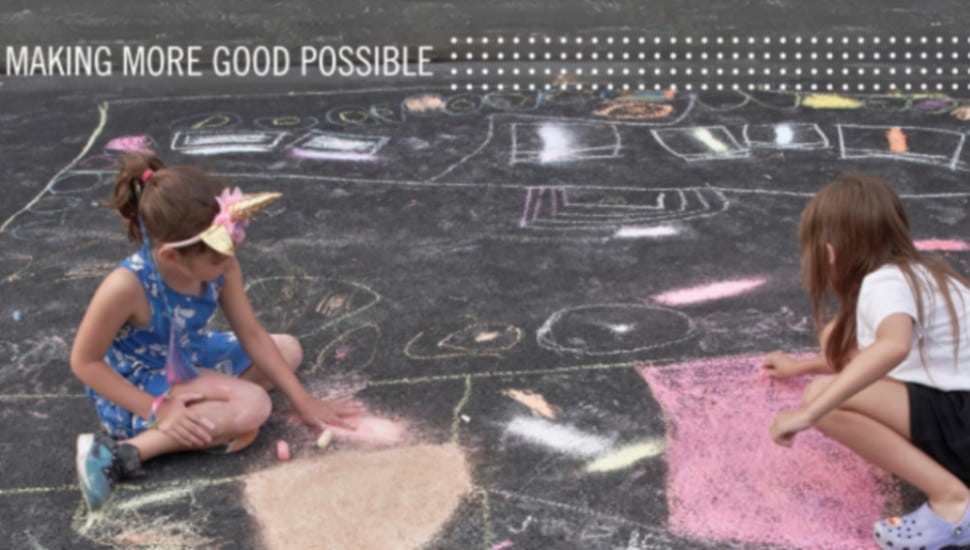 Children do chalk art on an asphalt lot.